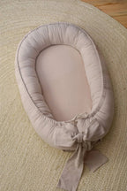 Beige organic baby nest top view, handmade linen baby lounger with decorative bow, CottonNest