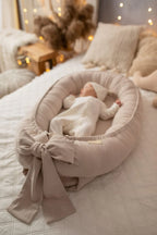 Beige linen baby nest for newborn, baby sleeping in organic lounger with bow, boho nursery