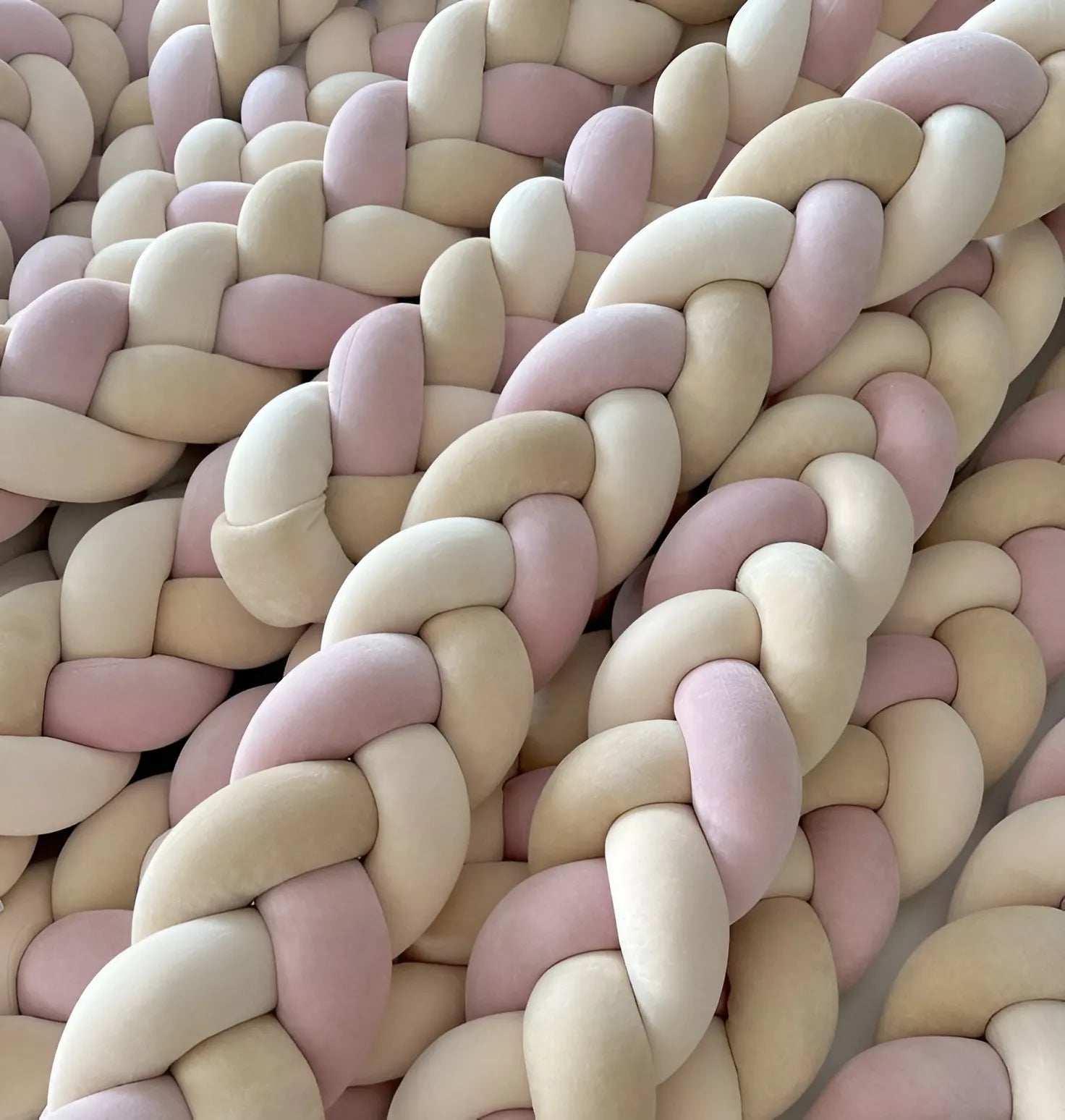 close up 3 strand braided crib bumper pink cream cotton velour texture, multiple bumpers stacked