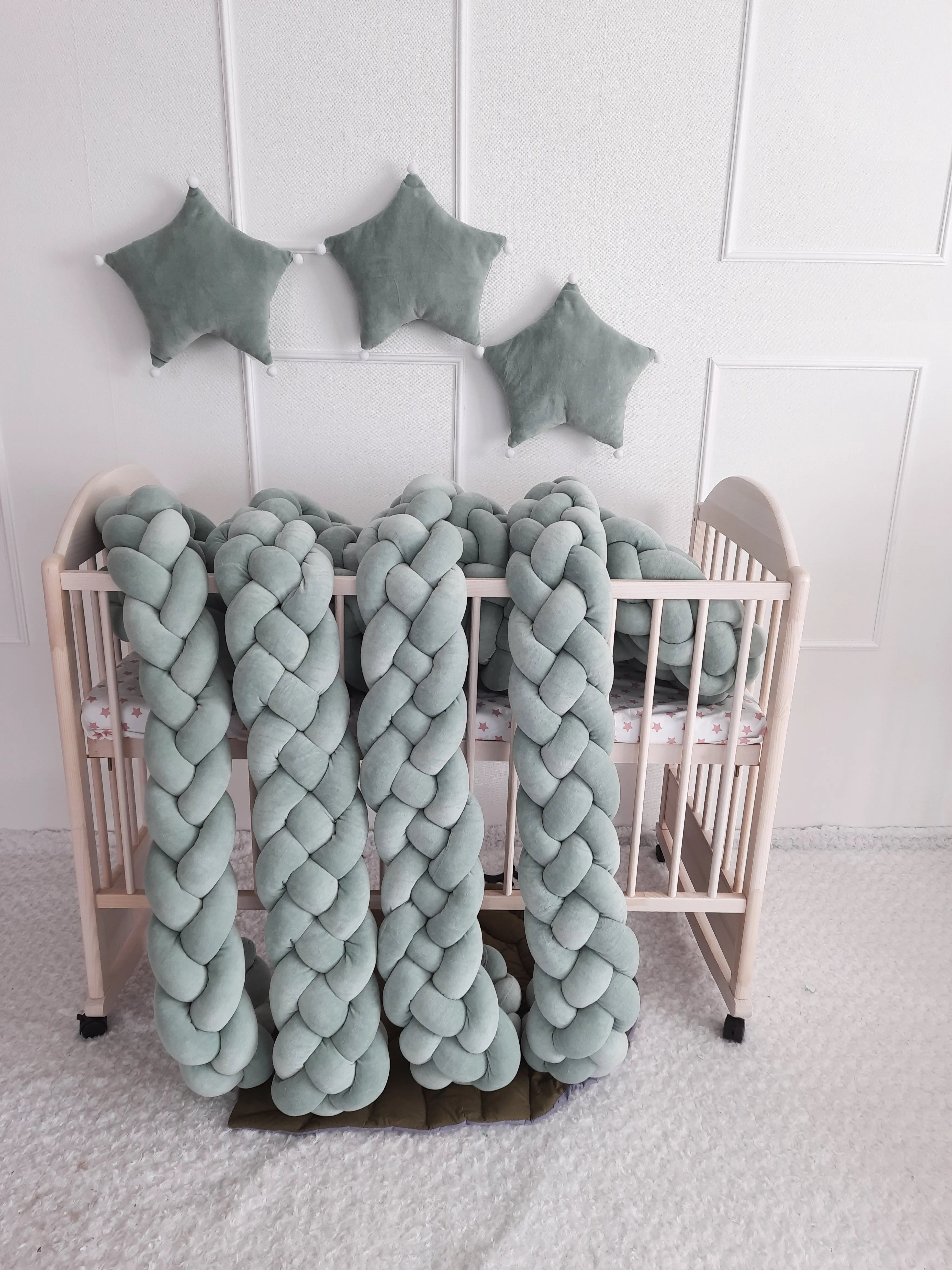 solid sage green 4 strand braided crib bumper draped over natural wood crib, nature nursery decor