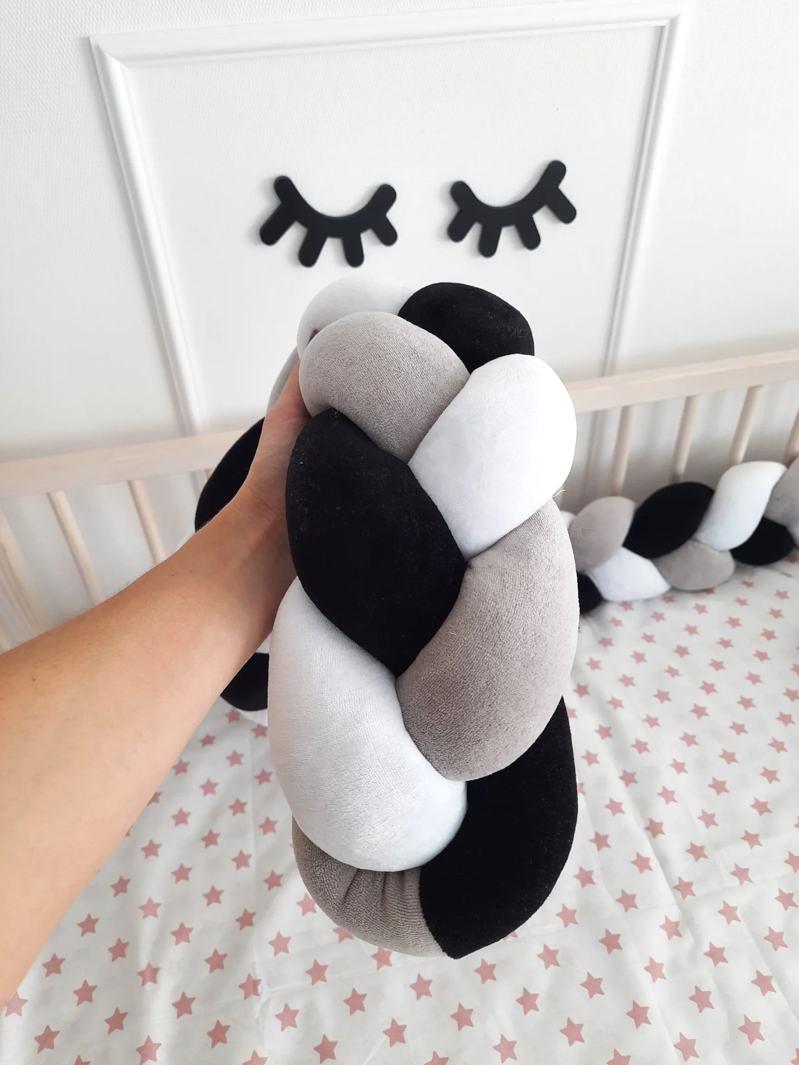 hand holding black white gray braided crib bumper cotton velour close-up