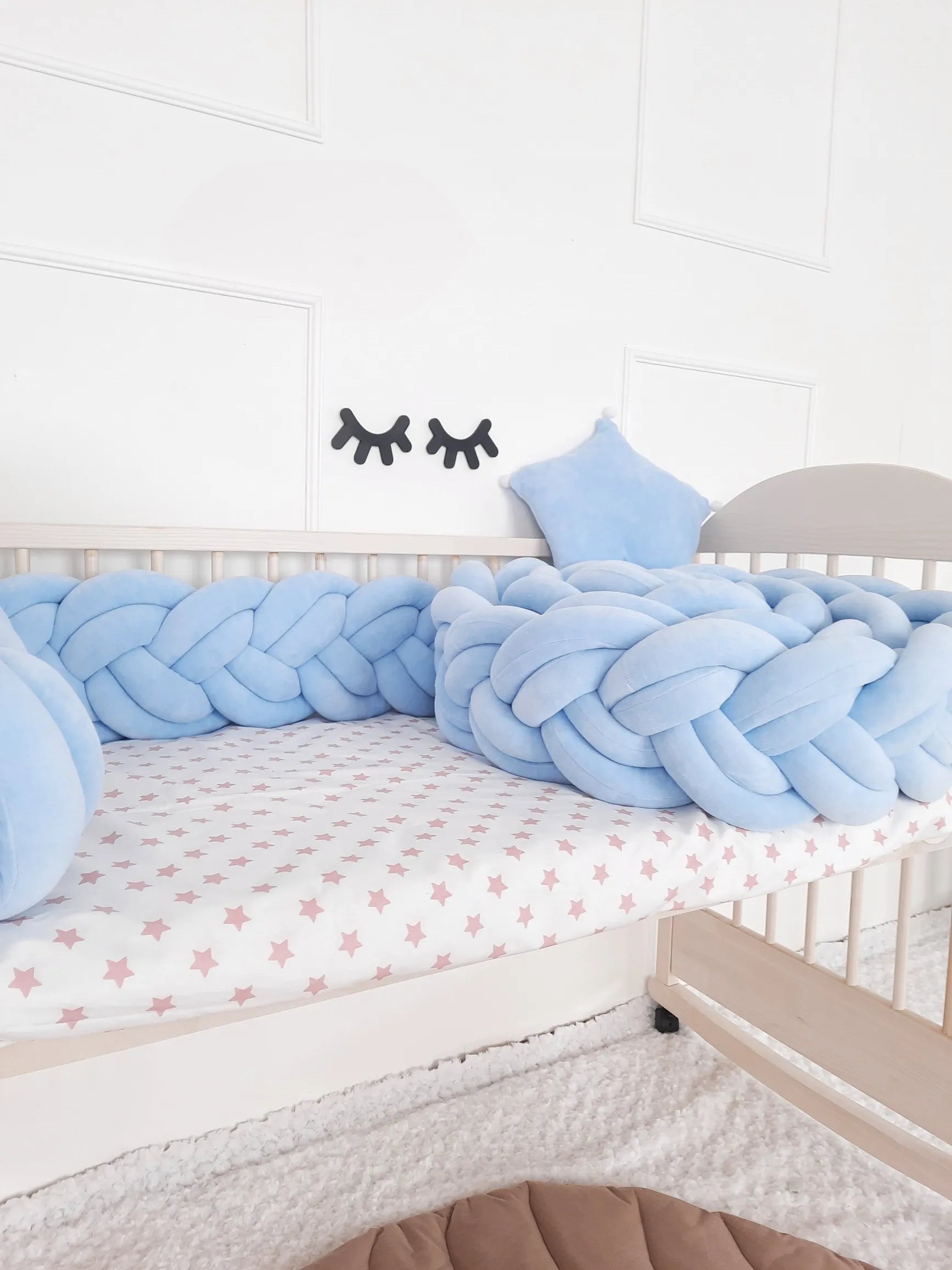 Double braided blue crib bumper with a baby crib in nursery