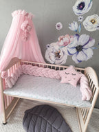 light pink woven crib bumper in wooden crib with pink canopy girl nursery