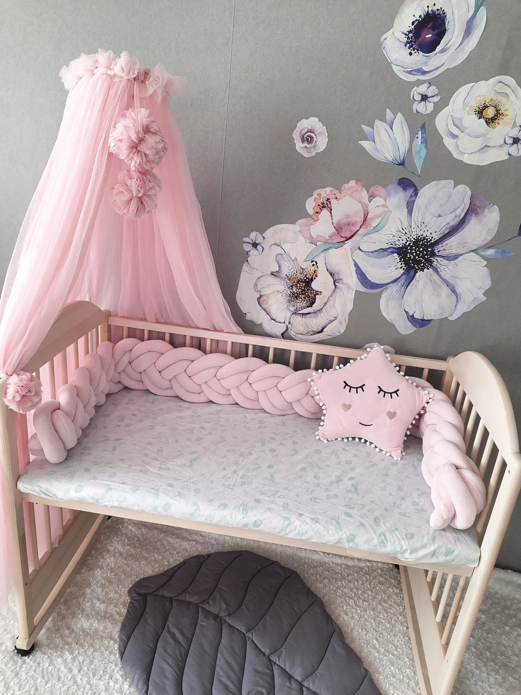 light pink woven crib bumper in wooden crib with pink canopy girl nursery