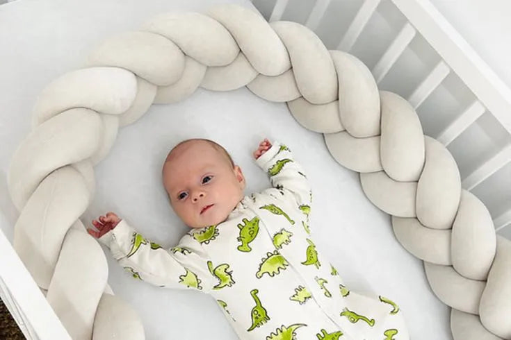 Baby lying in crib with milk 3-strand braided bumper, safe soft crib rail protection, CottonNest