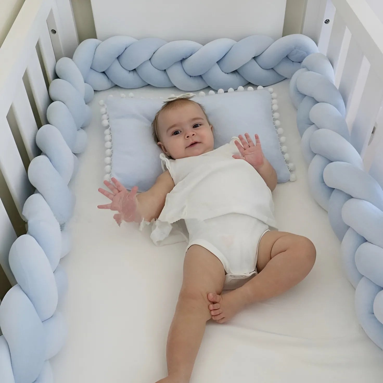 baby girl in white crib with solid blue 3 strand braided bumper, organic cotton, safe for newborns