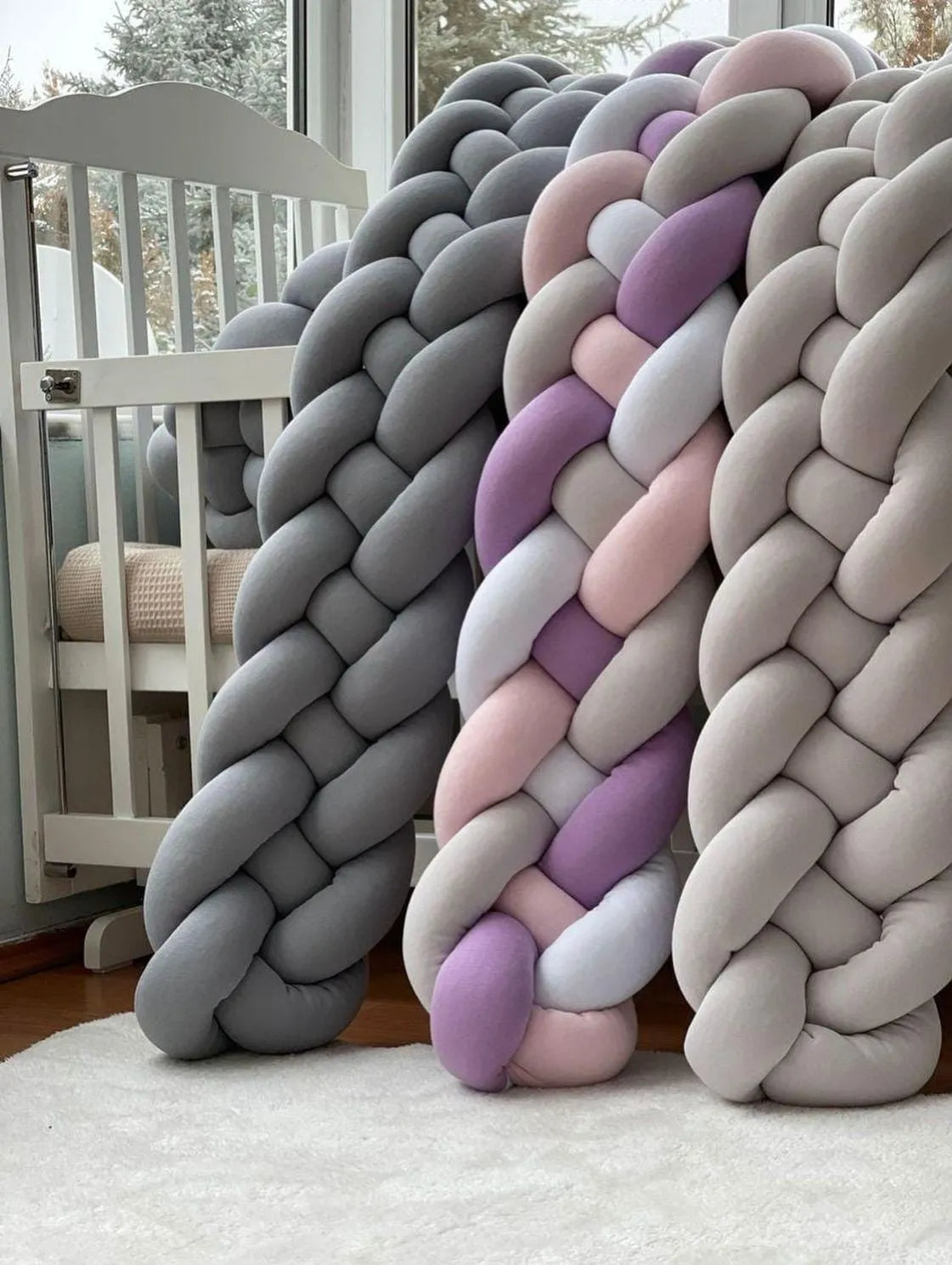 three 4 strand braided crib bumpers gray purple beige leaning against white crib, color options