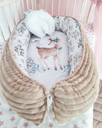 Cotton baby nest with deer print and pillow inside pink nursery crib, handmade organic newborn lounger