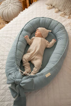 Newborn sleeping in light blue linen baby nest, organic baby boy lounger, gender neutral nursery