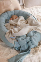 Close-up of newborn in light blue linen baby nest, hypoallergenic organic baby lounger, CottonNest