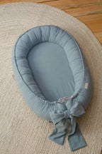Light blue linen baby nest top view, handmade organic baby lounger with bow, CottonNest