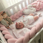 Baby girl in white crib with pink 3-strand braided bumper and swan toy, handmade cotton crib rail protection