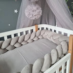 Light gray 3-strand braided crib bumper installed in white crib with canopy, soft cotton crib rail protection