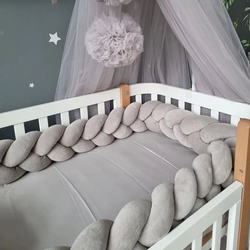 Light gray 3-strand braided crib bumper installed in white crib with canopy, soft cotton crib rail protection