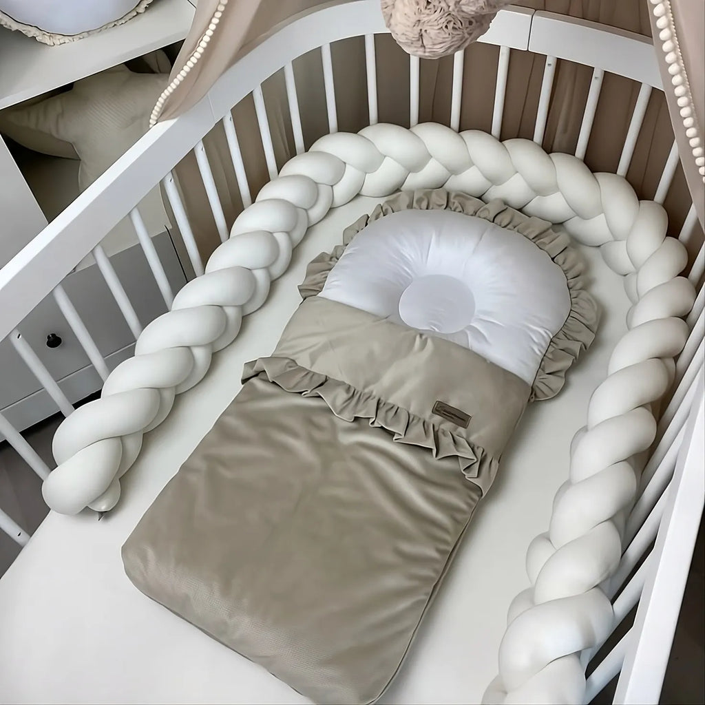 White 3 strand braided crib bumper in oval white crib with baby nest, minimal nursery