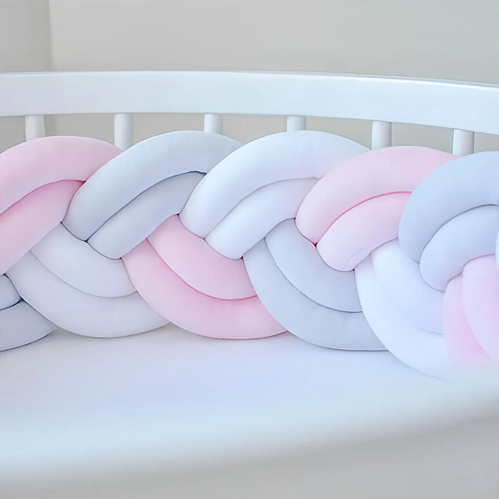 double braided cot bumper in pink and white color on the crib
