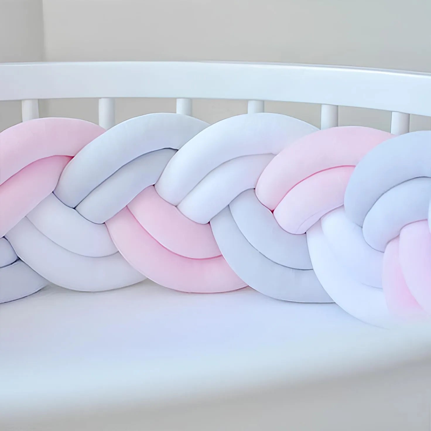 double braided cot bumper in pink and white color on the crib