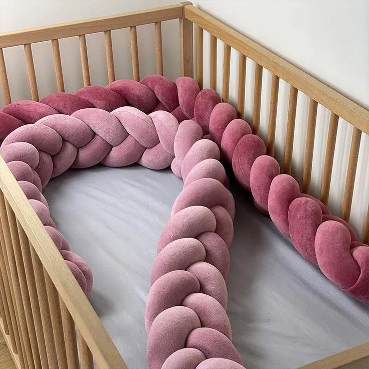 Two 3-strand braided crib bumpers in rose gold and fresia colors lining full wooden crib, handmade cotton baby girl nursery bumper