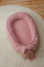 Light pink linen baby nest top view, handmade organic baby girl lounger with decorative bow, CottonNest