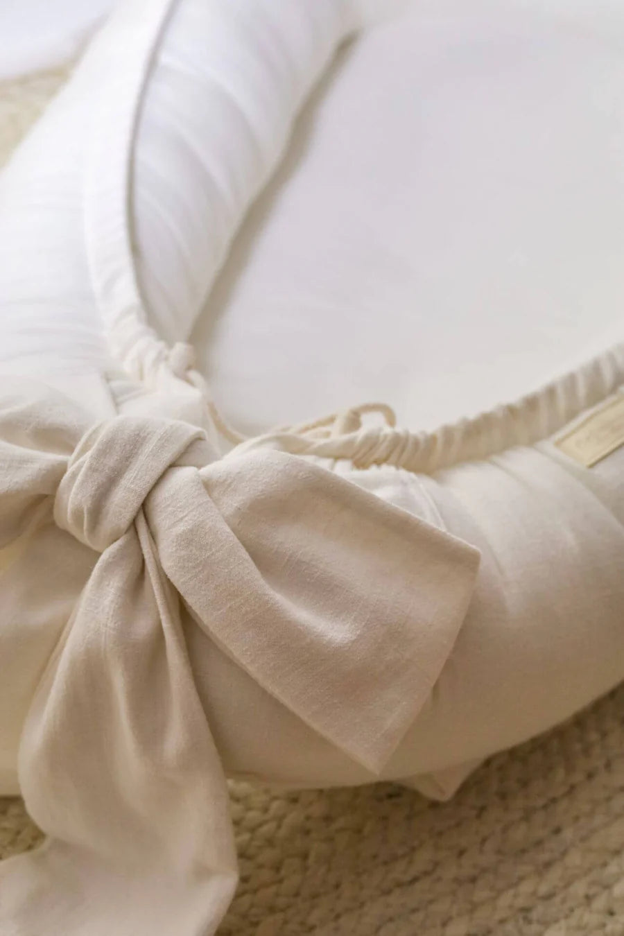 Decorative bow detail on ivory linen baby nest, handmade organic newborn lounger, CottonNest