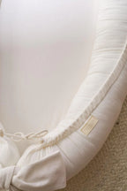 Close-up of ivory linen baby nest fabric and CottonNest label, OEKO-TEX certified organic baby lounger