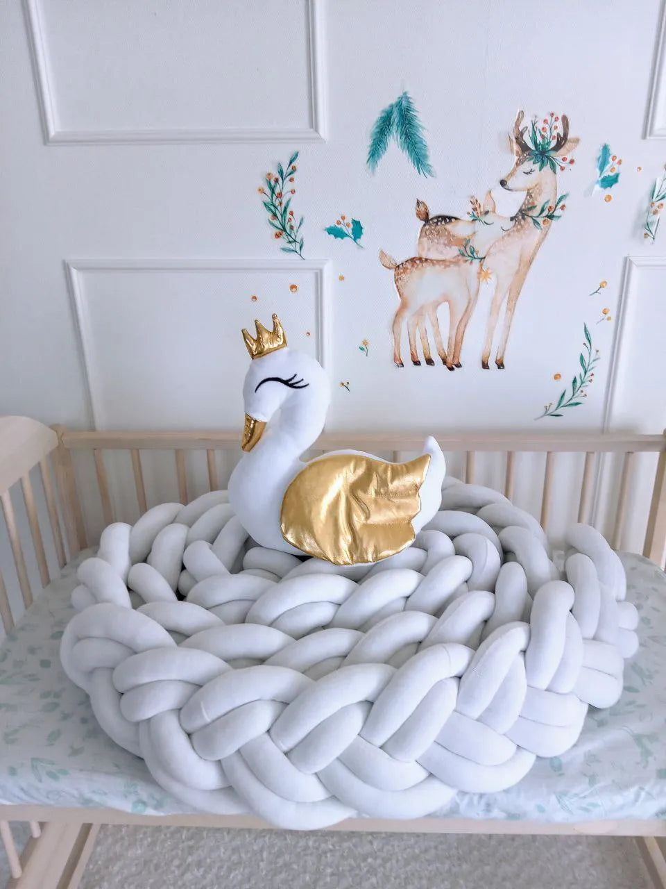 solid white double braided crib bumper coiled in natural wood crib, swan pillow, deer wall decor